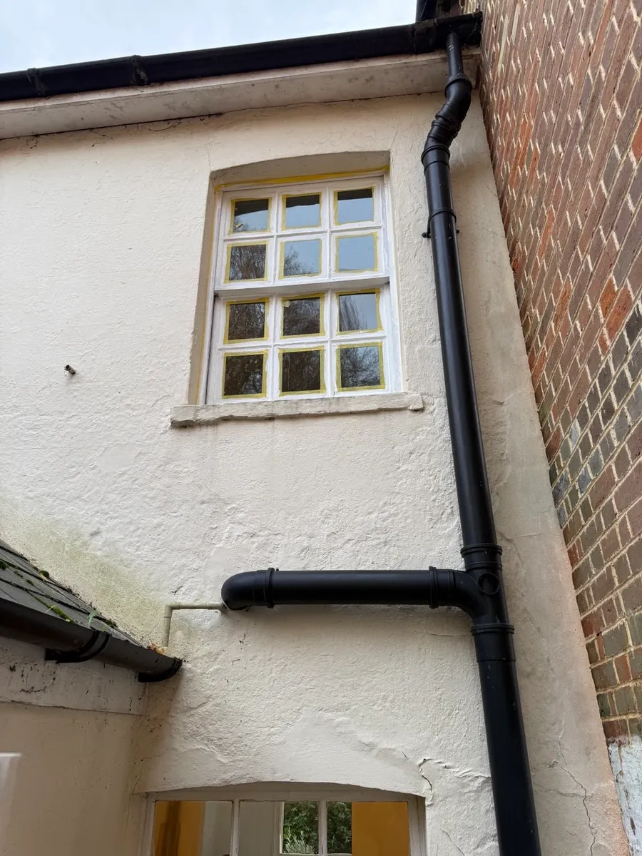 Timber sash window masked with yellow tape during repainting on a rendered house exterior